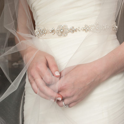 detail of the brides hands clasping her veil together