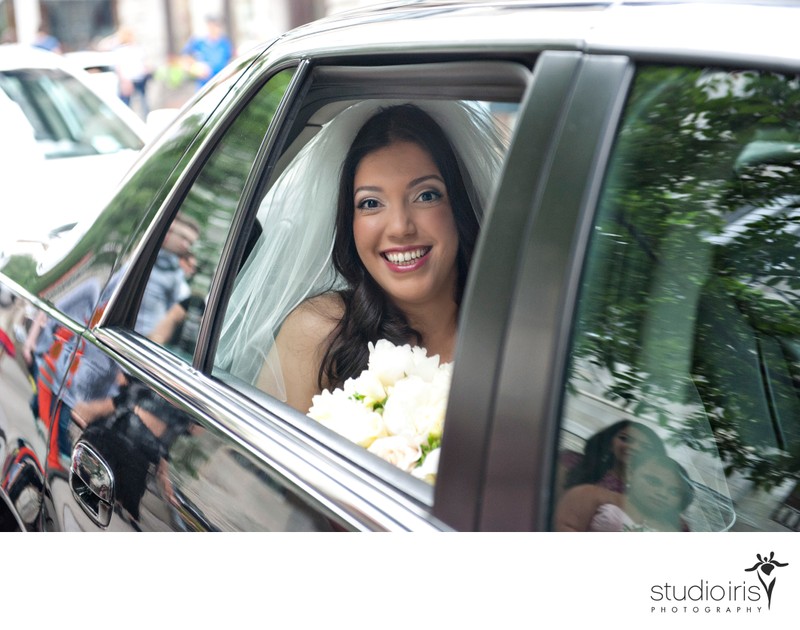 Bride smiling through limousine window at Notre Dame Basilica in Montreal