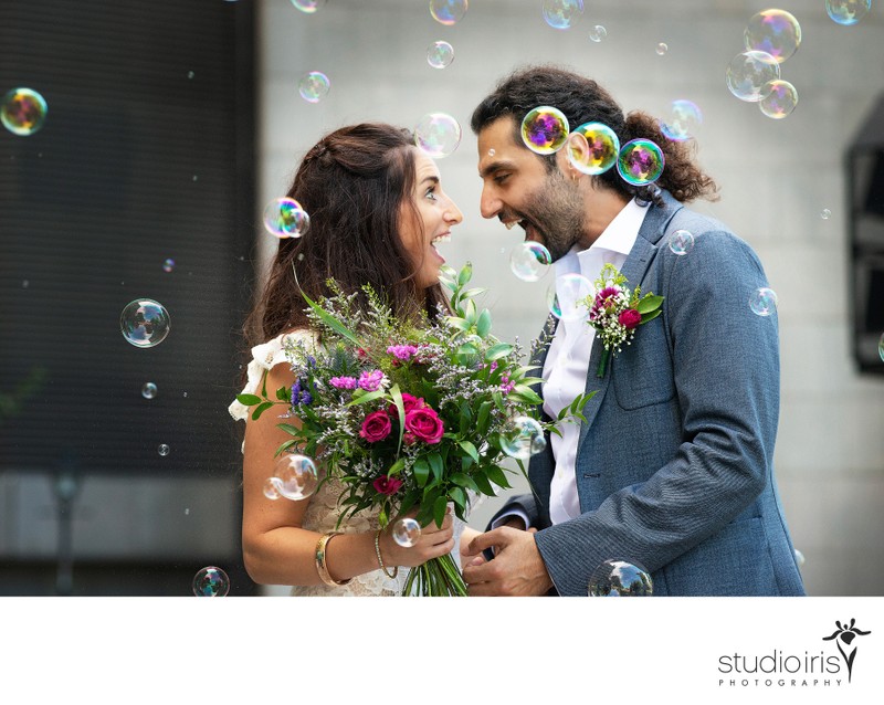 Newlyweds in cloud of bubbles looking at each other in amazement  after their Montreal City Hall Wedding