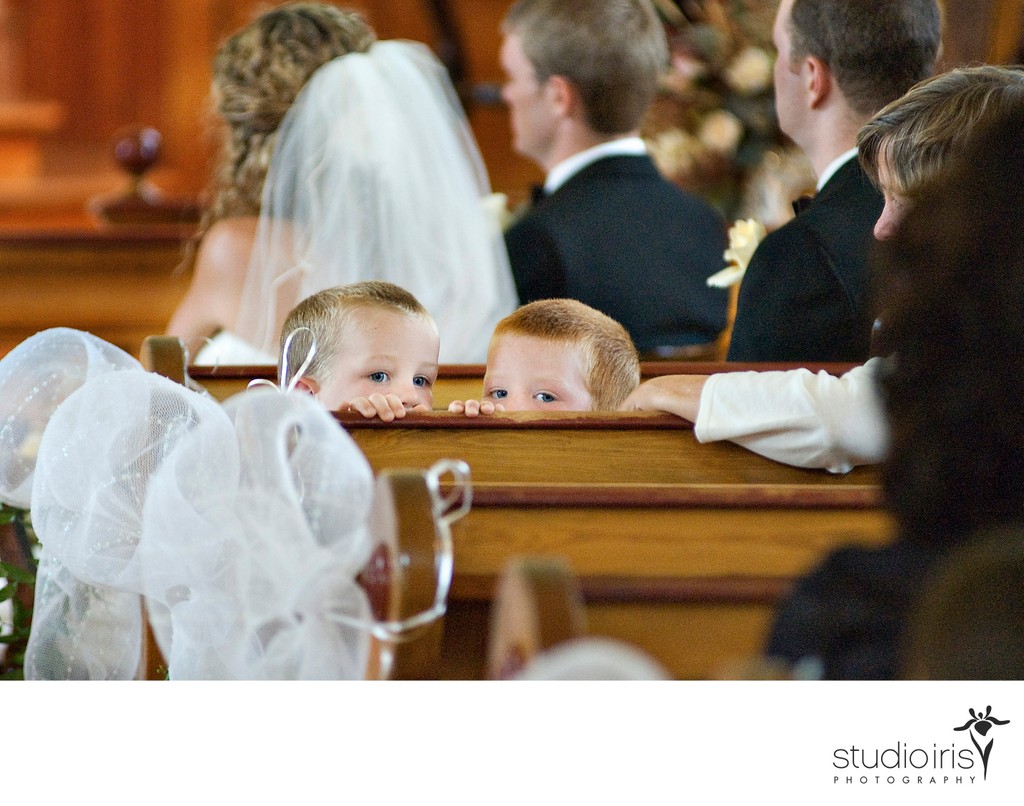 Two boys peeking mischievously over the pew during a wedding ceremony in Quebec's Eastern Townships