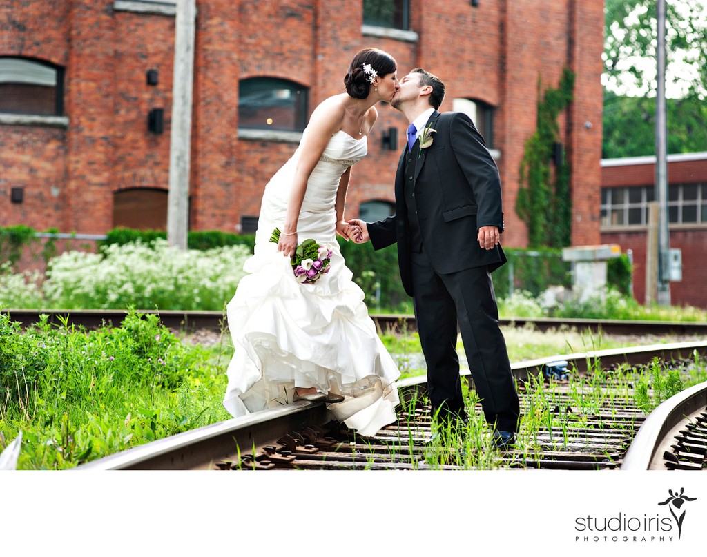 Bride and groom kissing on the railway tracks near wedding venue L'Ambroisie et L'Espace Canal
