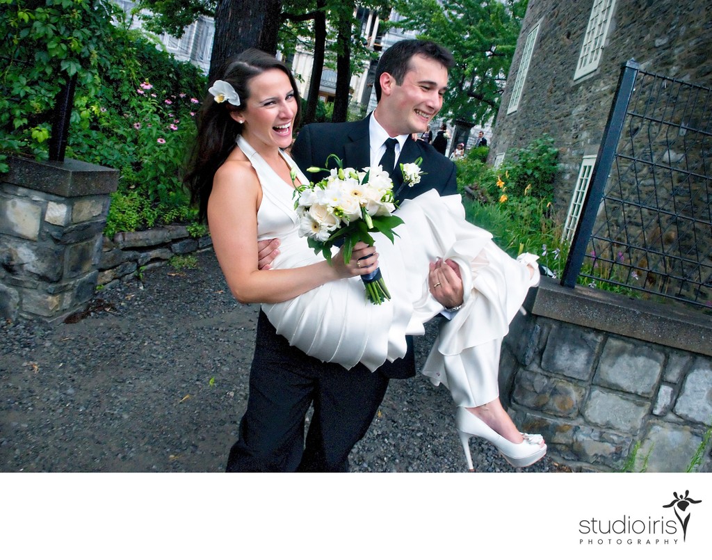 Groom running with bride in his arms after wedding ceremony at Chateau Ramezay in Montreal