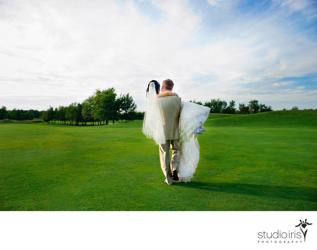 Groom carrying bride in his arms across the fairway at Golf St-Raphaël