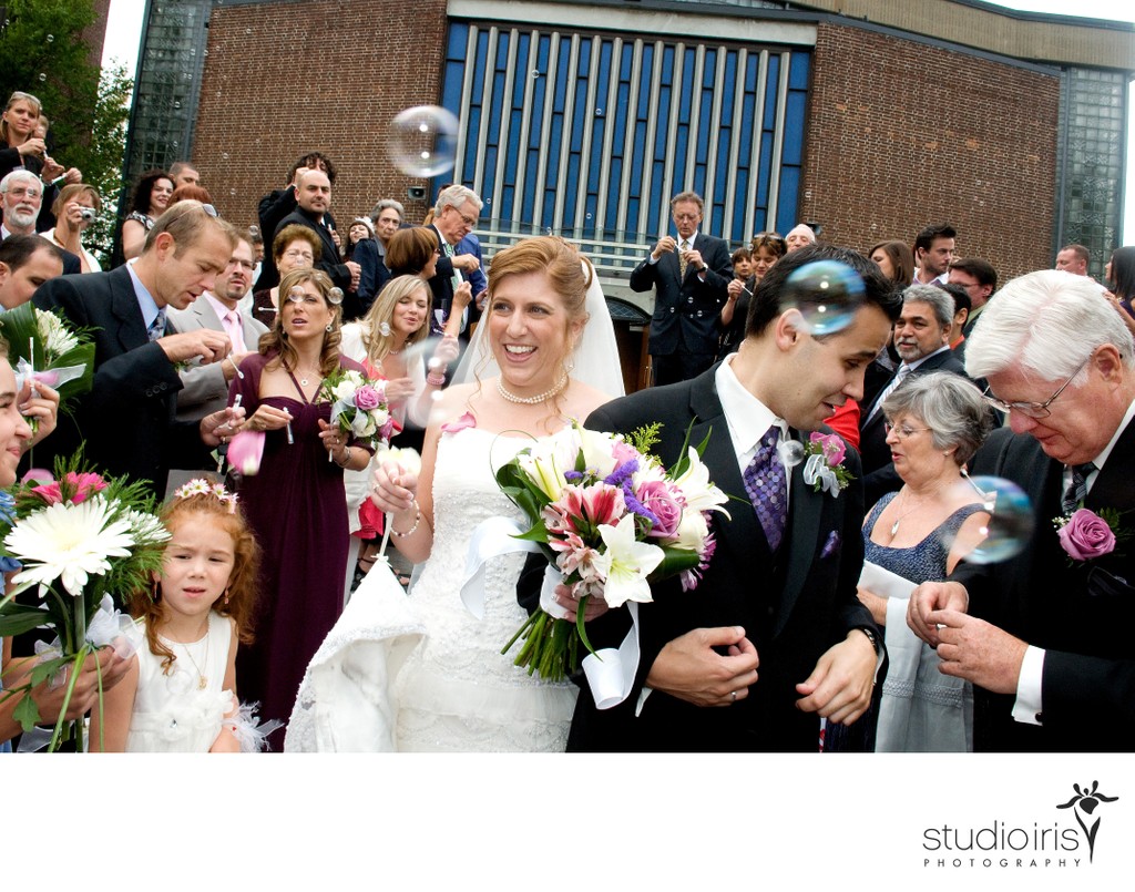 Bride and groom getting jostled in crowd as they leave St. George Cathedral after wedding