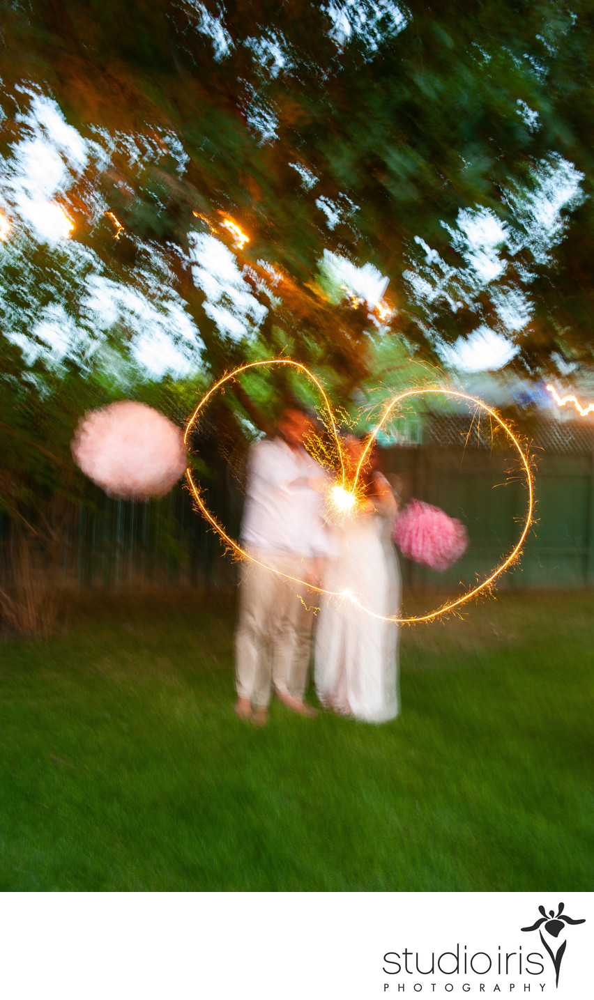 Newlyweds make a heart at dusk with a flashlight at their backyard wedding in Montreal