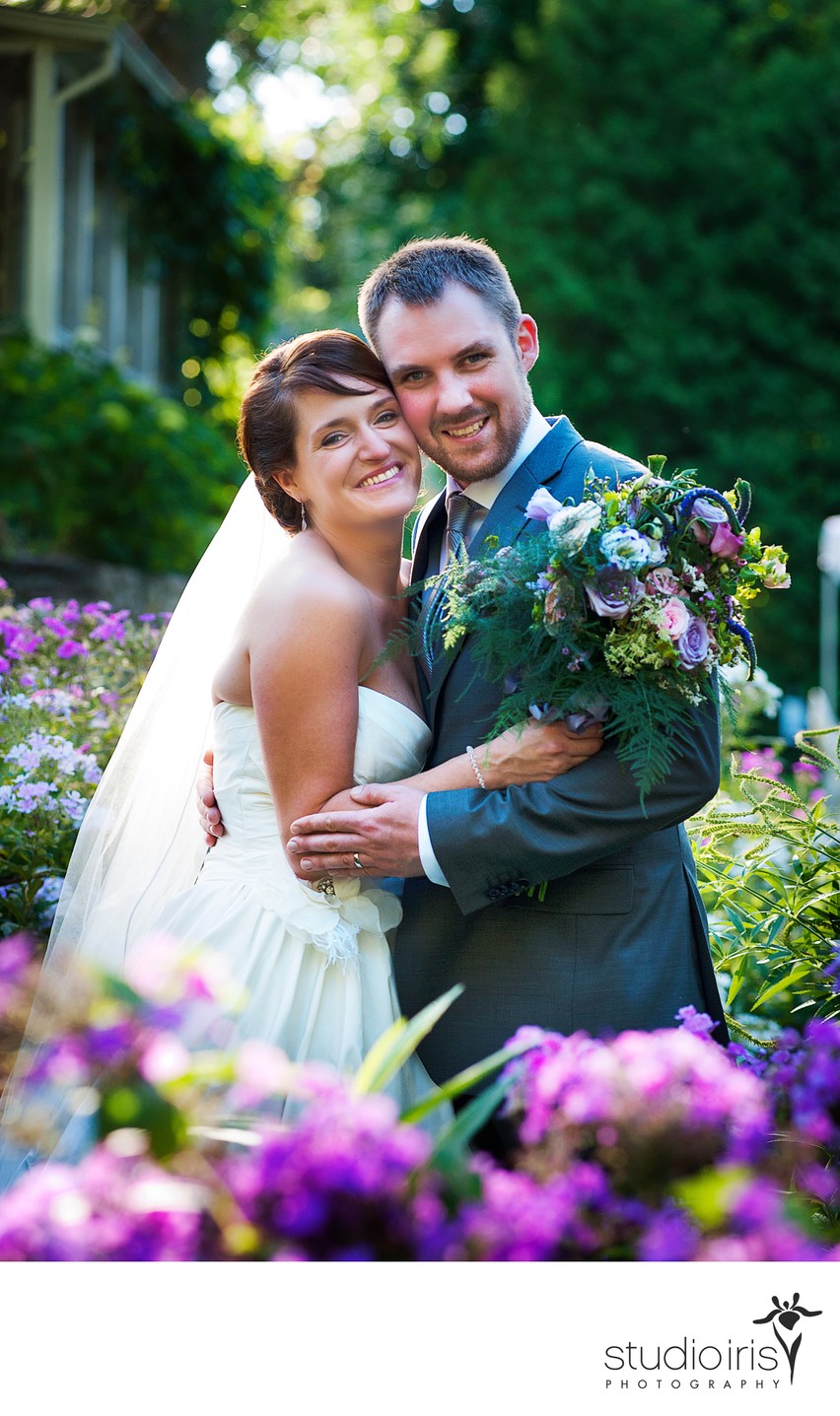Bride and groom embracing and looking deeply happy in flower garden