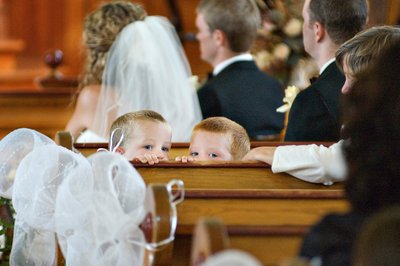Two boys peeking mischievously over the pew during a wedding ceremony in Quebec's Eastern Townships