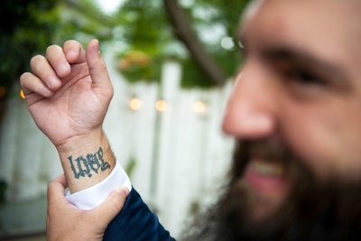 Groom showing off his LOVE tattoo on his forearm on his wedding day 