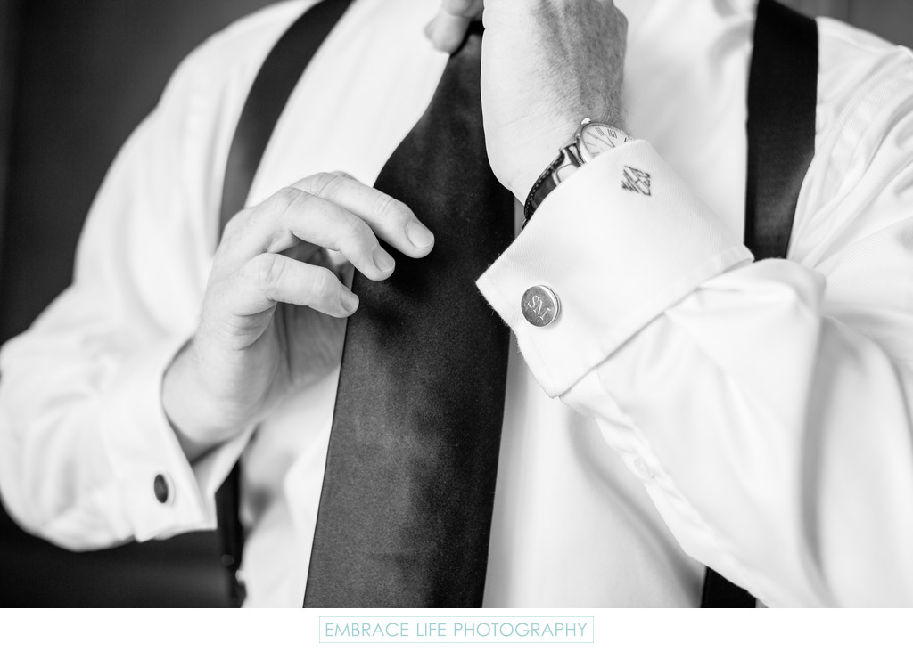 Groom Adjusting Tie With Monogrammed Cufflinks