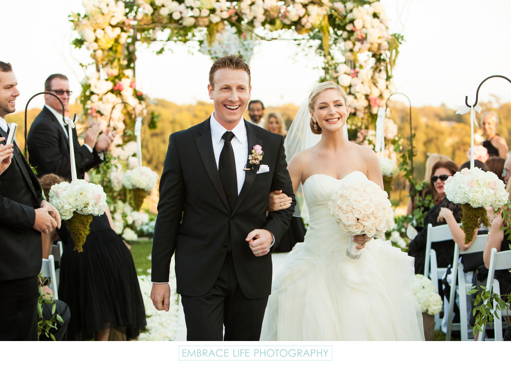 Smiling Bride and Groom Walking Down the Aisle