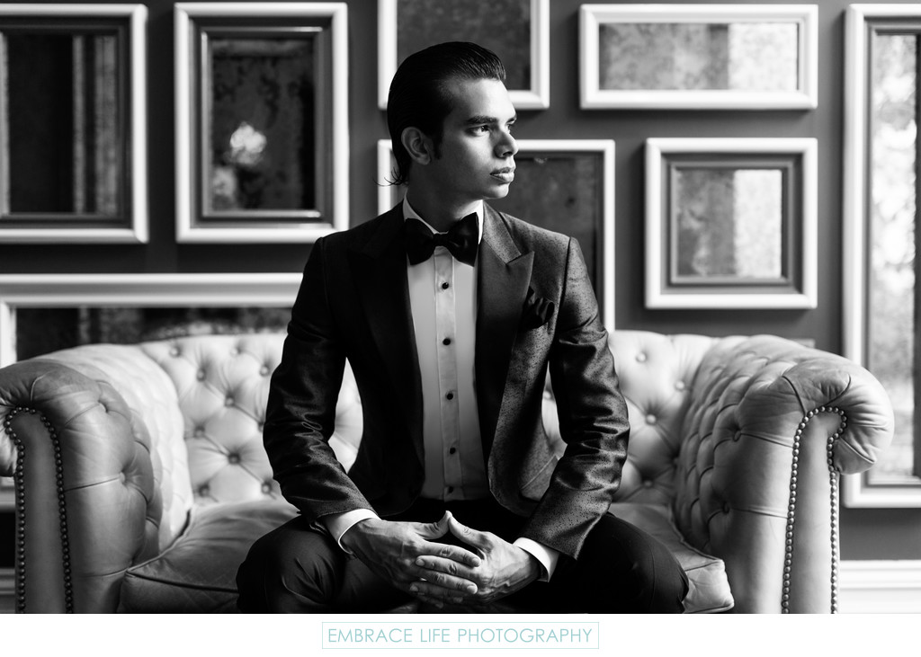 Black and White Photo of Groom Sitting on Tufted Sofa