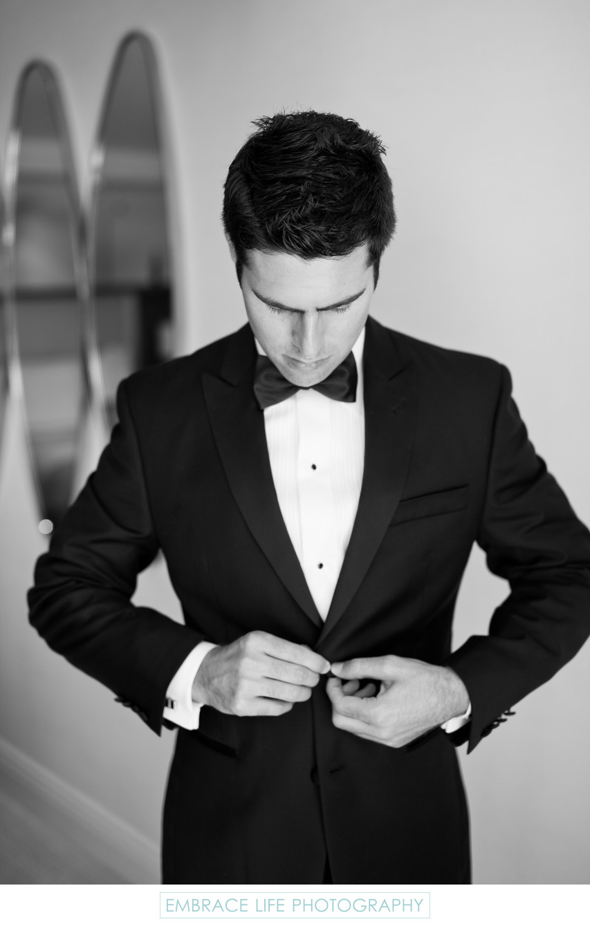 Groom in Black Bow Tie Buttons his Tuxedo Jacket