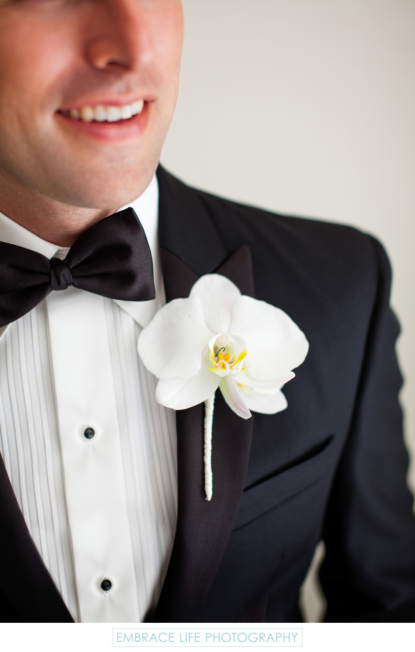 White Orchid Boutonniere on Groom's Black Tie Tuxedo