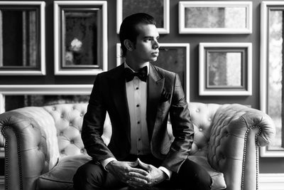 Black and White Photo of Groom Sitting on Tufted Sofa