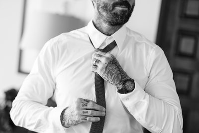 Groomsman with Tattooed Hands Tying Necktie