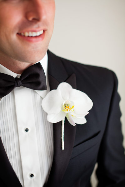 White Orchid Boutonniere on Groom's Black Tie Tuxedo