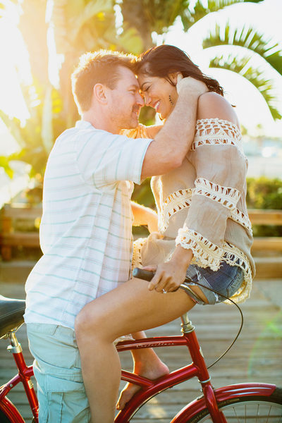 backlit sunshine couple on beach cruiser bikes at beach