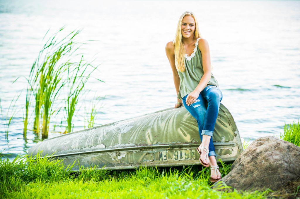 Cute senior portrait of a blonde girl posing on an camouflage boat