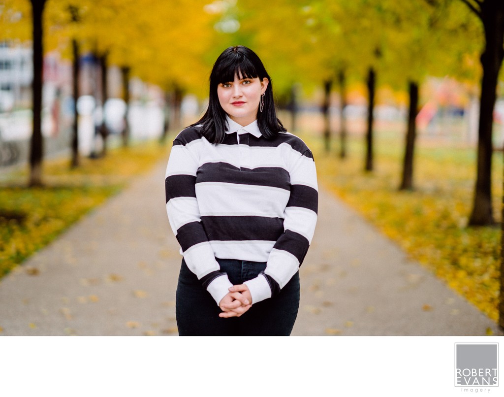 A senior portrait of dark haired girl against bright yellow fall colors 