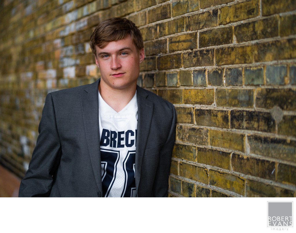 An old brick wall with a shallow depth of field help draw your attention to this boys senior portrait