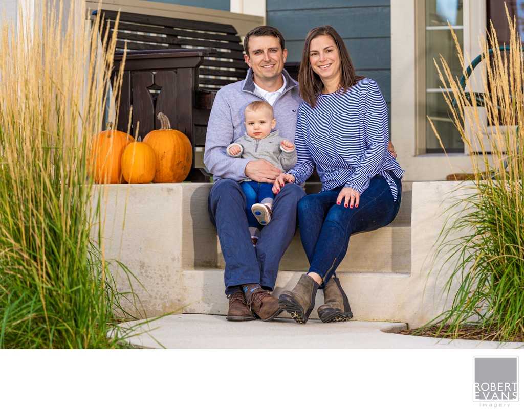 Parents and baby seated by pumpkins
