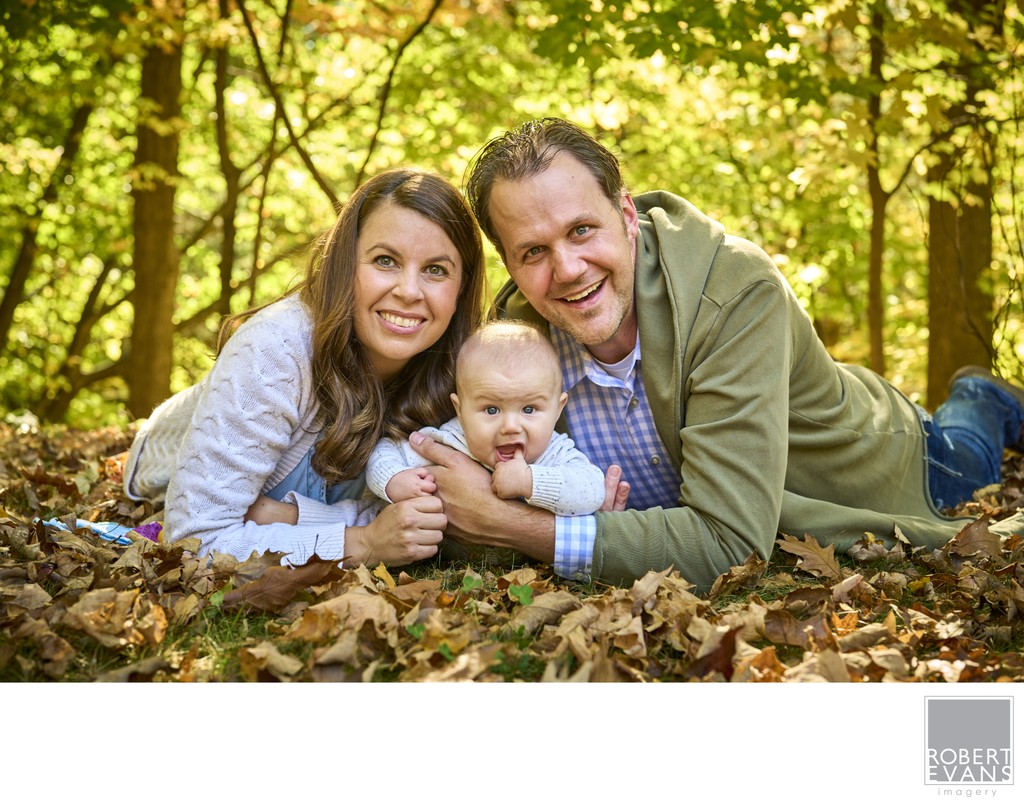 Parents and baby in autumn leaves