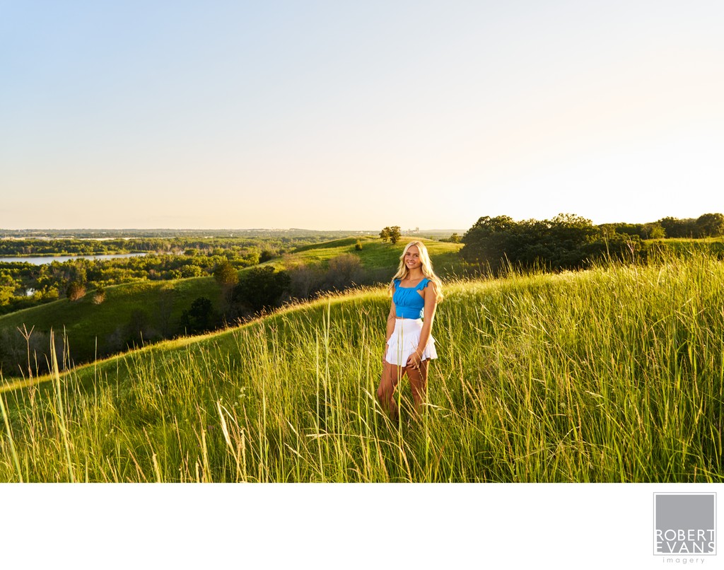 Beautiful backlit senior portrait at sunset on a rolling hill. 