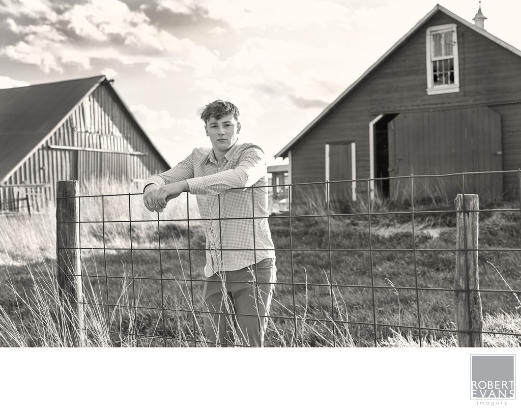 Senior portrait of boy leaning against a fence on grandpa's farm.