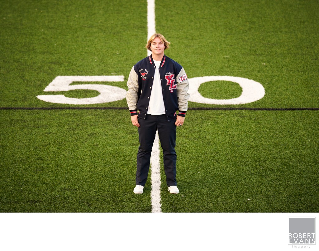 Yorba Linda Mustangs Football Player and Senior wearing his Letterman's jacket on the 50 yard line