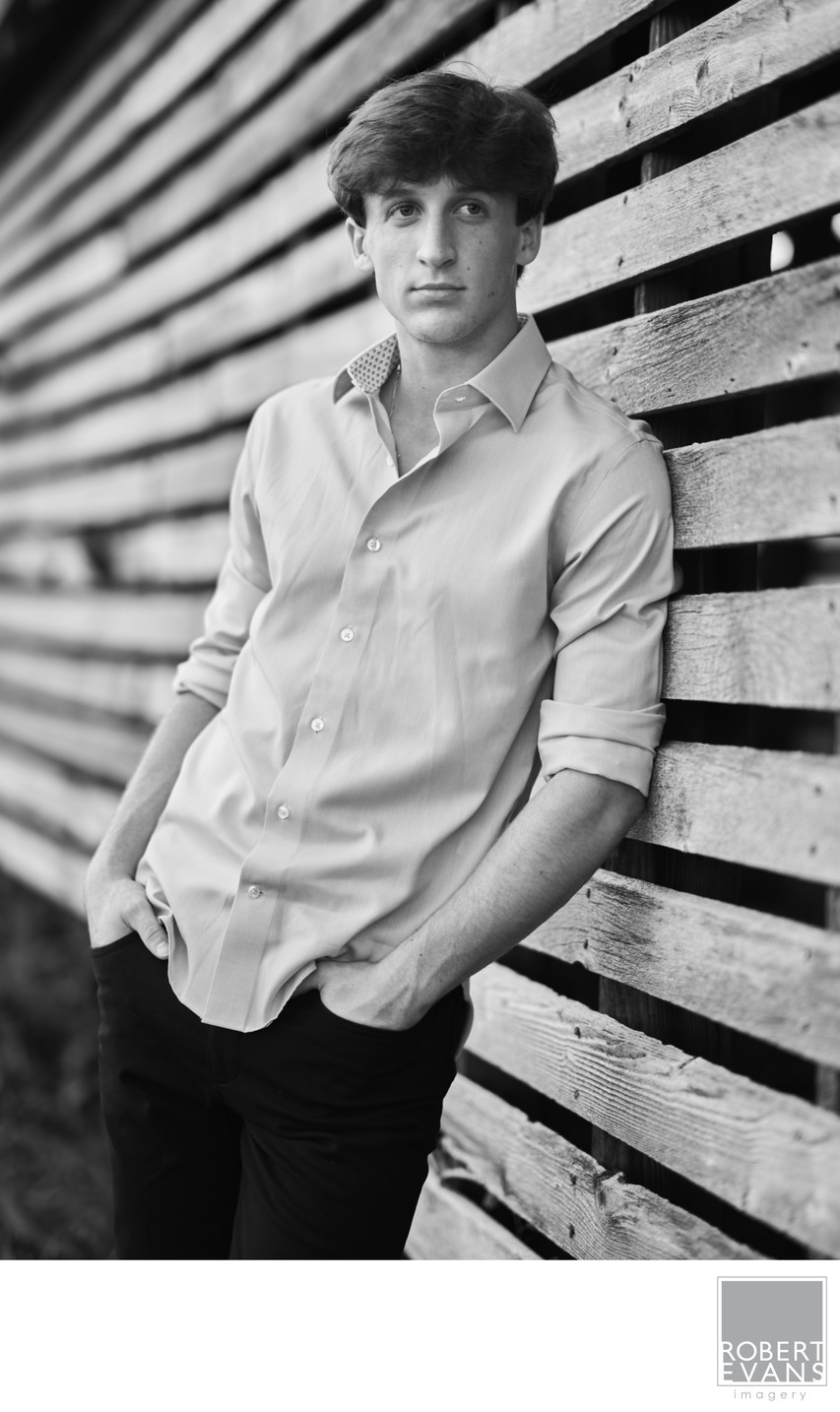 Relaxed half body senior portrait in black&white against on old wooden wall