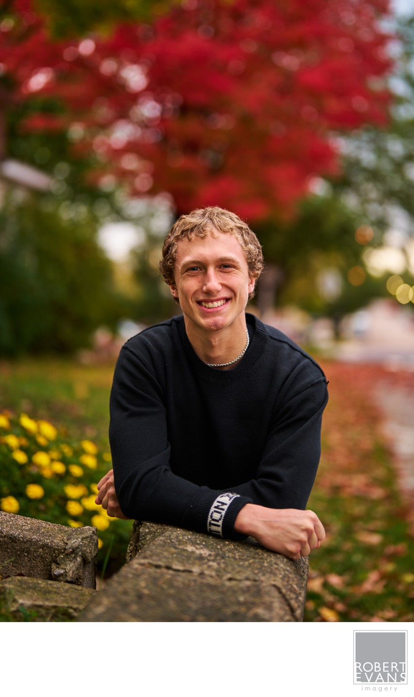 Senior portrait with stunning bright red maple tree as backdrop
