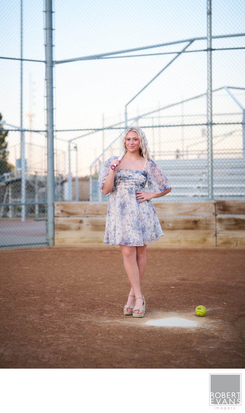 Softball themed senior portrait with softball bat behind home plate. 