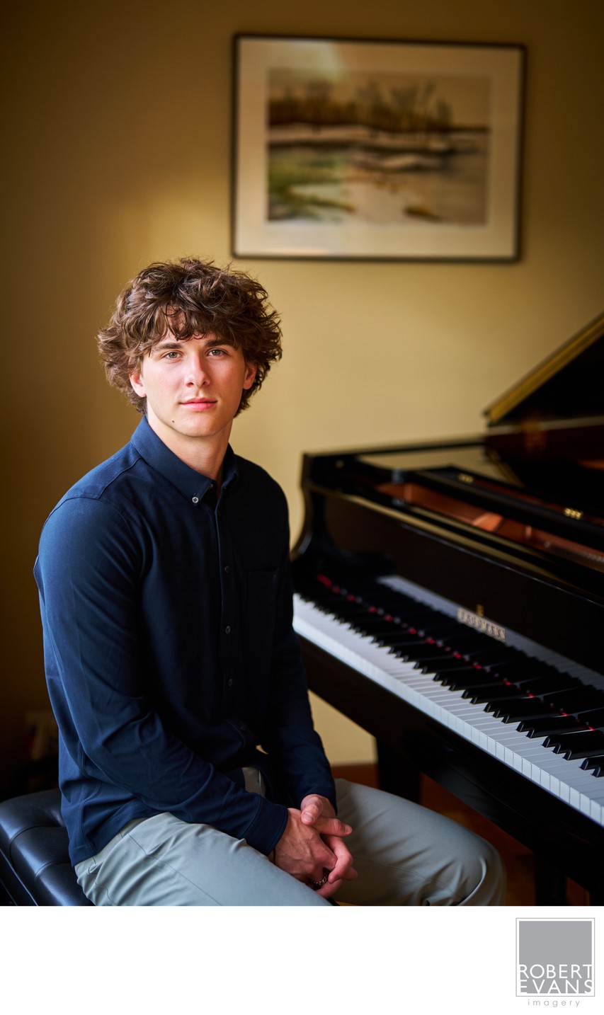 A portrait of a high school senior seated at his piano