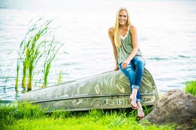 Cute senior portrait of a blonde girl posing on an camouflage boat