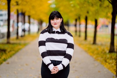 A senior portrait of dark haired girl against bright yellow fall colors 