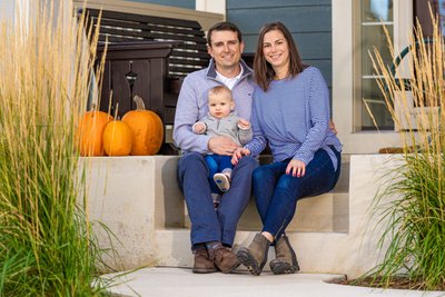 Parents and baby seated by pumpkins