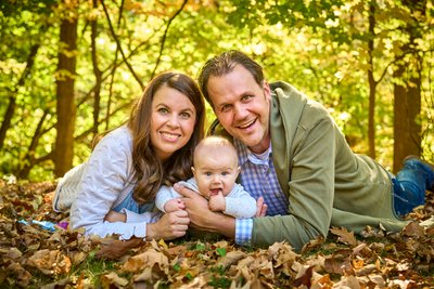 Parents and baby in autumn leaves