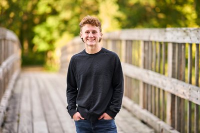 Relaxed half body senior portrait on a bridge.