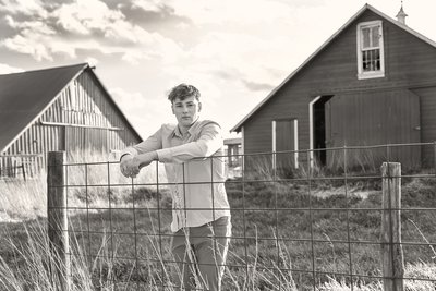 Senior portrait of boy leaning against a fence on grandpa's farm.