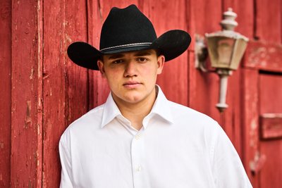 Black Cowboy Hat  Senior Senior Portrait by a Red Barn