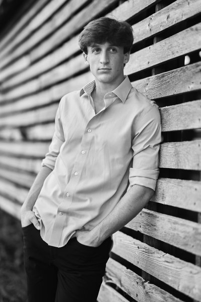 Relaxed half body senior portrait in black&white against on old wooden wall