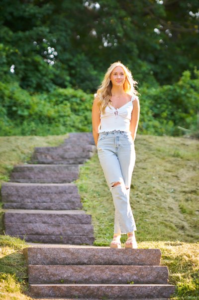 Backlit senior portrait of a Minnetonka senior girl standing by stone staircase 