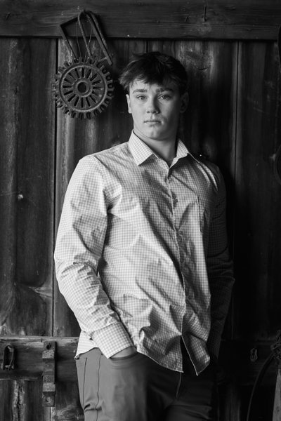 Dramatic black and white portrait of a high school senior boy in an old barn.