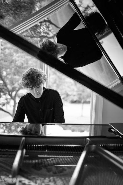 Black and white senior portrait of a high school senior playing piano