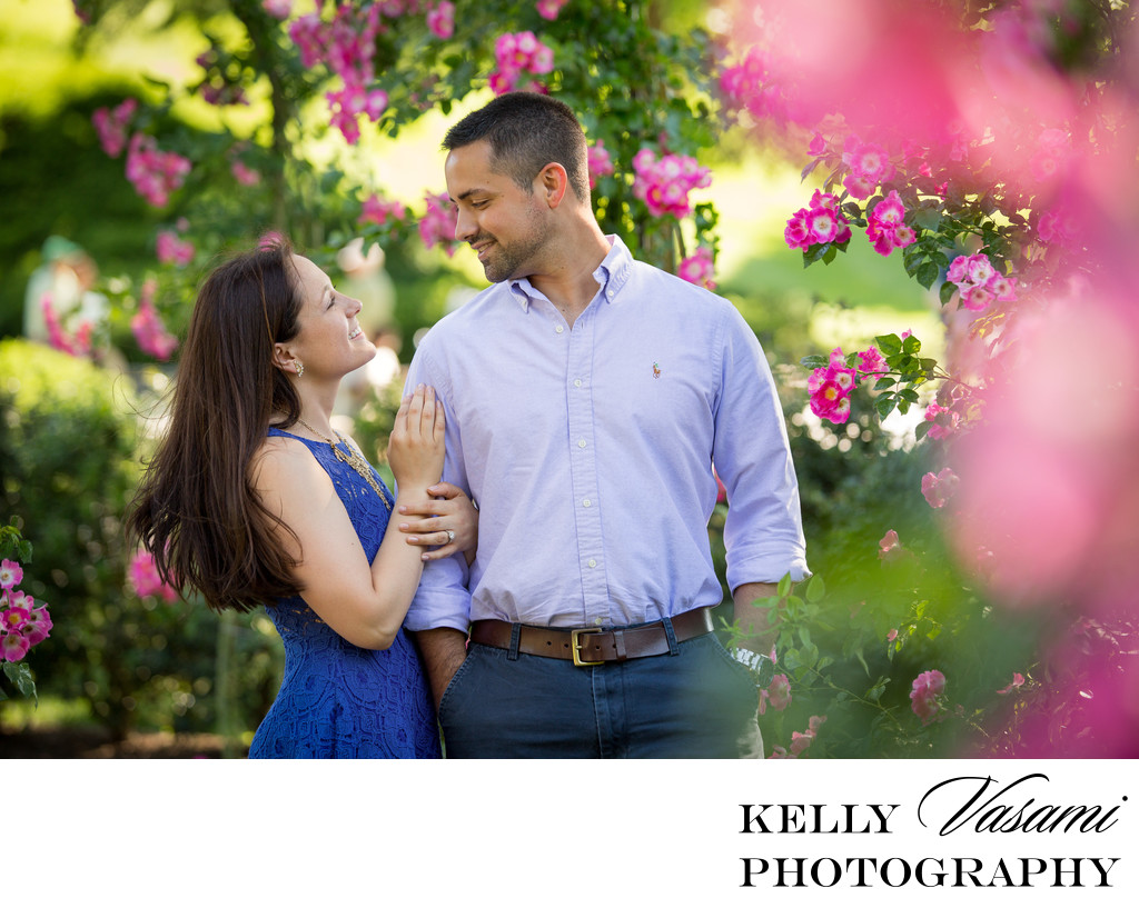 Couple surrounded by pink roses at engagement session