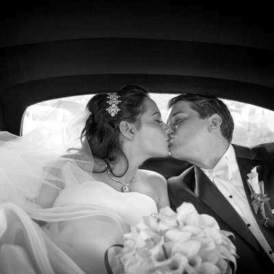 bride and groom kissing in classic limo