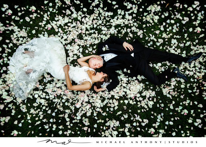 Bride and groom lay in a bed of flowers.
