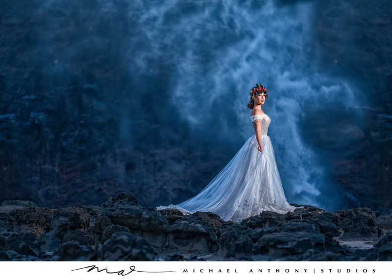 Bride poses on rocky terrain near ocean