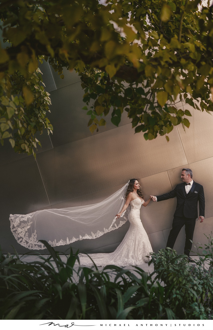 Bride and Groom Pose in front of architecture