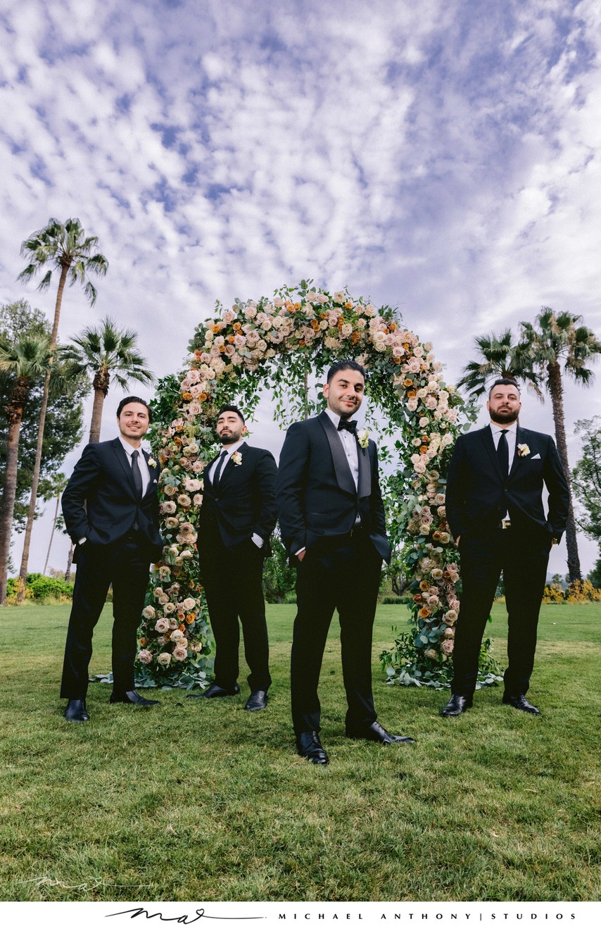 Stylish Groomsmen Under Floral Arch with Palm Trees